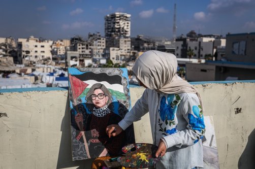 Fifteen-year-old painter Sara Abu Saade paints with the destroyed buildings of Gaza City in the background, Gaza Strip, Palestine, Dec. 23, 2025. (AA Photo)