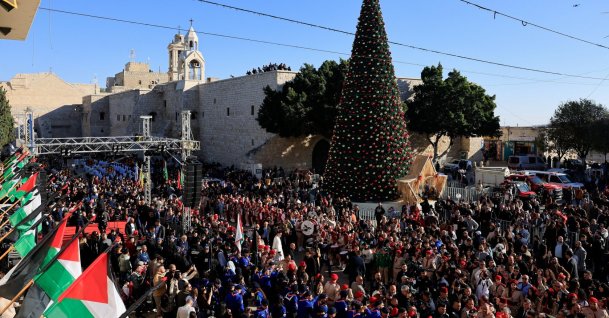 People gather next to the Christmas tree at Manger Square on the day of Christmas events with Cardinal Pierbattista Pizzaballa, Latin Patriarch of Jerusalem, on Christmas Eve, in the Old City of Bethlehem in the Israeli-occupied West Bank, Dec. 24, 2025. (Reuters Photo)