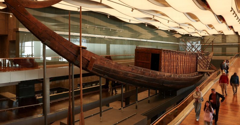 People walk next to King Khufu's boat, also known as the Solar Boat, as work to restore it starts with wooden planks, part of the 1,650-piece structure being installed on a metal frame through Egyptian-Japanese cooperation with two Japanese universities, marking the start of preparations for the second boat's public display at the Grand Egyptian Museum (GEM), near the Giza Pyramid Complex, Giza, Egypt, Dec. 23, 2025. (Reuters Photo)