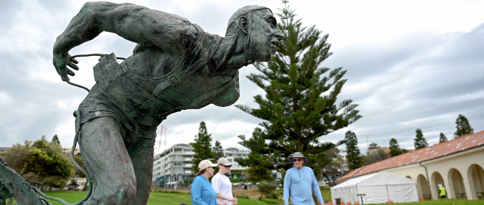People walk past the Surf Life Saver statue at Bondi Beach as life gradually returns to normal following seven days of mourning, in Sydney, Australia, Dec. 22, 2025. (AFP Photo)