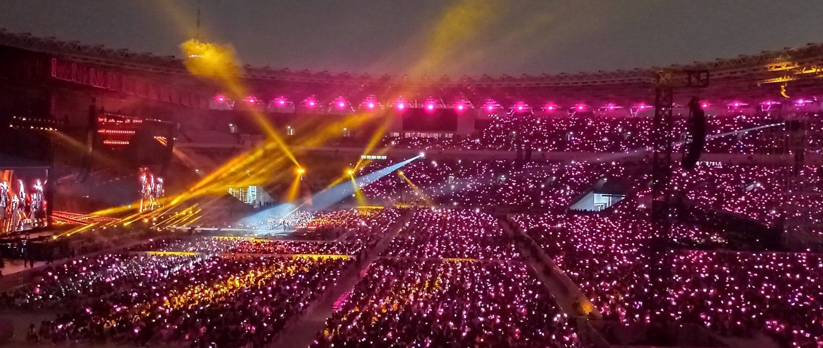K-pop girl group Blackpink performing at a full stadium as fans wave lightsticks. (Shutterstock Photo)