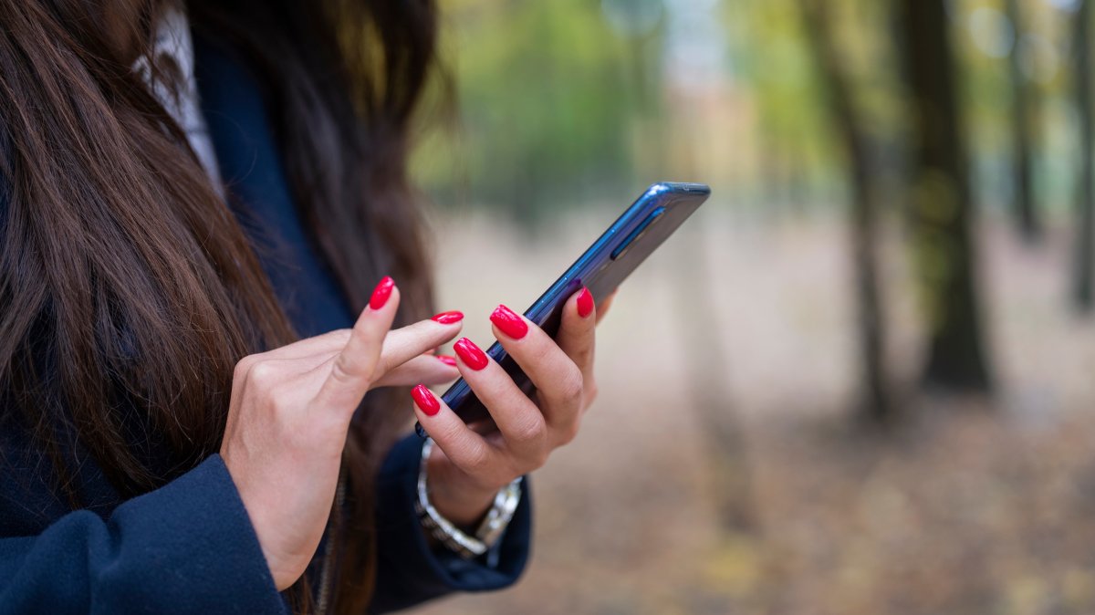 A woman checks the news on her smartphone. (Shutterstock Photo)