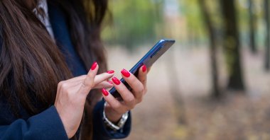 A woman checks the news on her smartphone. (Shutterstock Photo)