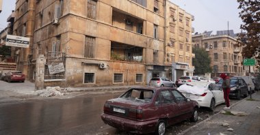 A man stands near damaged cars after attacks by the YPG, Aleppo, Syria, Dec. 23, 2025. (Reuters Photo)