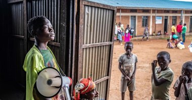 A young refugee from stands with a megaphone to give instructions to other refugees at a food distribution point at Nyarushishi Transit Camp, Rusizi district, DRC, Dec. 11, 2025. (AFP Photo)