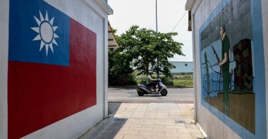 A motorist commutes past paintings on a wall of the Taiwan flag and a soldier in Taiwan's Kinmen, May 18, 2024. (AFP Photo)