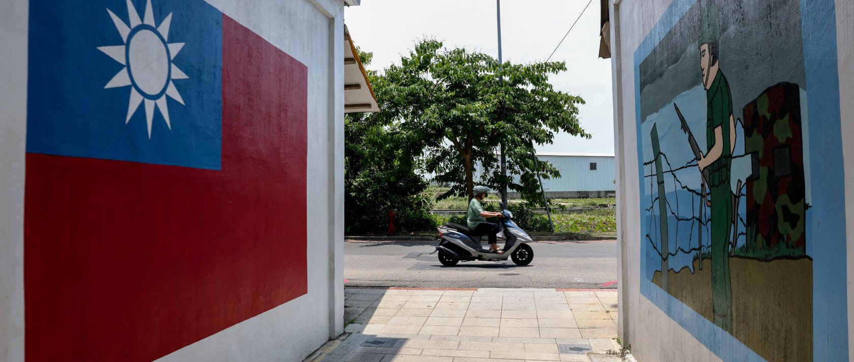 A motorist commutes past paintings on a wall of the Taiwan flag and a soldier in Taiwan's Kinmen, May 18, 2024. (AFP Photo)