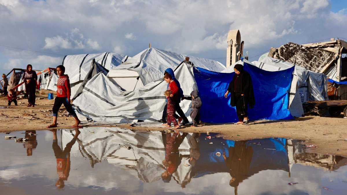 Displaced Palestinians walk past a large pool of rainwater accumulated near tent shelters as the region experiences rain and cold winter conditions, in Gaza City, central Gaza Strip, Palestine, Dec. 28, 2025. (AFP Photo)