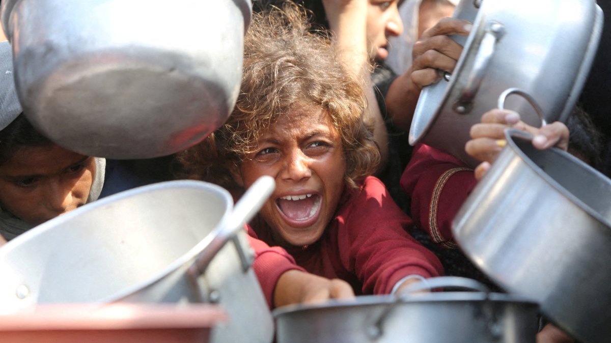 A child reacts surrounded by pots as Palestinians wait to receive food from a charity kitchen in Khan Younis, southern Gaza Strip, Aug. 21, 2025. (Reuters Photo)