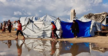 Displaced Palestinians walk past a large pool of rainwater accumulated near tent shelters as the region experiences rain and cold winter conditions, in Gaza City, central Gaza Strip, Palestine, Dec. 28, 2025. (AFP Photo)