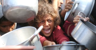 A child reacts surrounded by pots as Palestinians wait to receive food from a charity kitchen in Khan Younis, southern Gaza Strip, Aug. 21, 2025. (Reuters Photo)