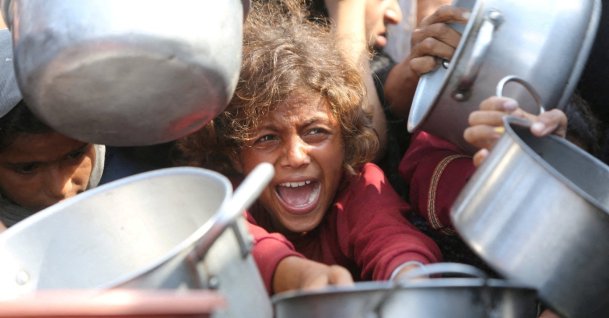 A child reacts surrounded by pots as Palestinians wait to receive food from a charity kitchen in Khan Younis, southern Gaza Strip, Aug. 21, 2025. (Reuters Photo)