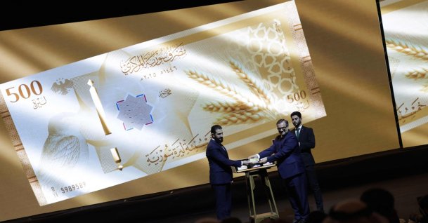 Syria's President Ahmed al-Sharaa (L) and Syria's Central bank chief Abdul Qadir al-Hasriya (R) hold one of the country's new revamped currency notes at the Conference Palace in the capital Damascus, Syria, Dec. 29, 2025. (AFP Photo)