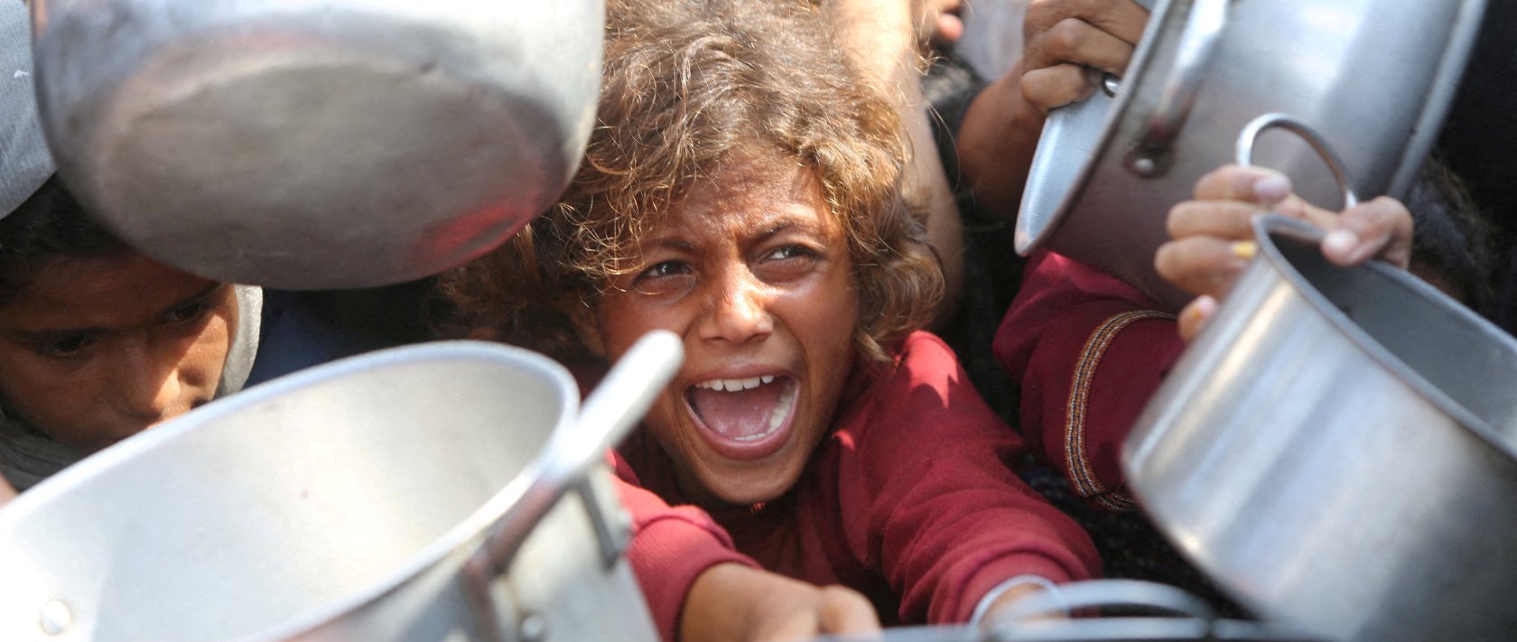 A child reacts surrounded by pots as Palestinians wait to receive food from a charity kitchen in Khan Younis, southern Gaza Strip, Aug. 21, 2025. (Reuters Photo)