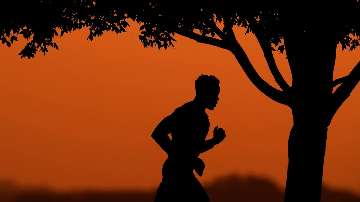 A man is silhouetted against the sky at sunset as he jogs in a park at the close of a hot summer day, Kansas City, Mo., U.S., Aug. 1, 2022. (AP Photo)
