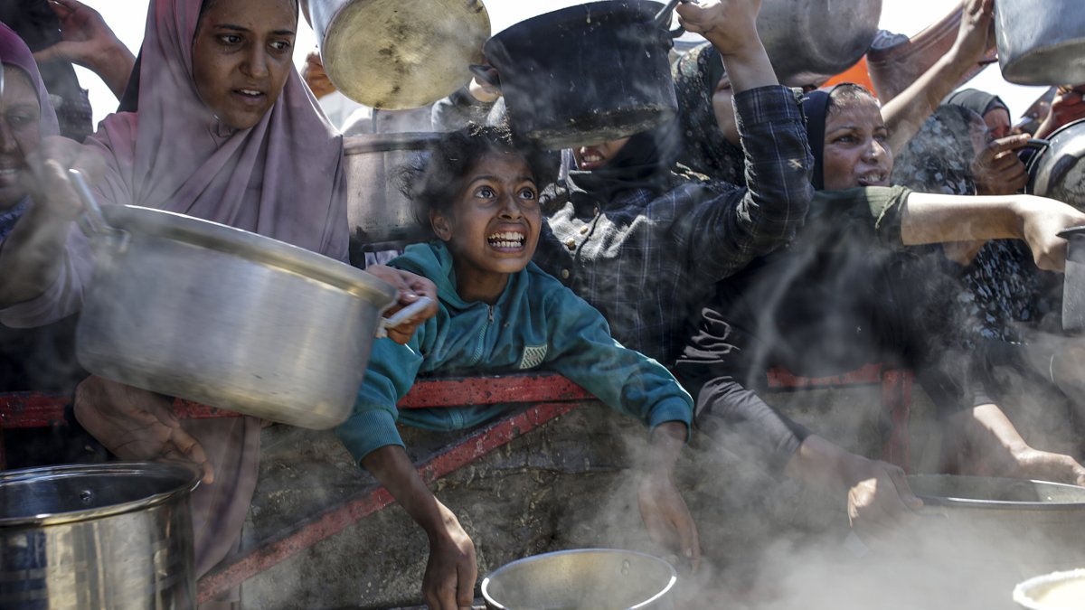 Internally displaced Palestinians, including children, hold pots as they gather to receive food from a charity kitchen, in Gaza City, Gaza Strip, Aug. 4, 2025. (EPA File Photo)