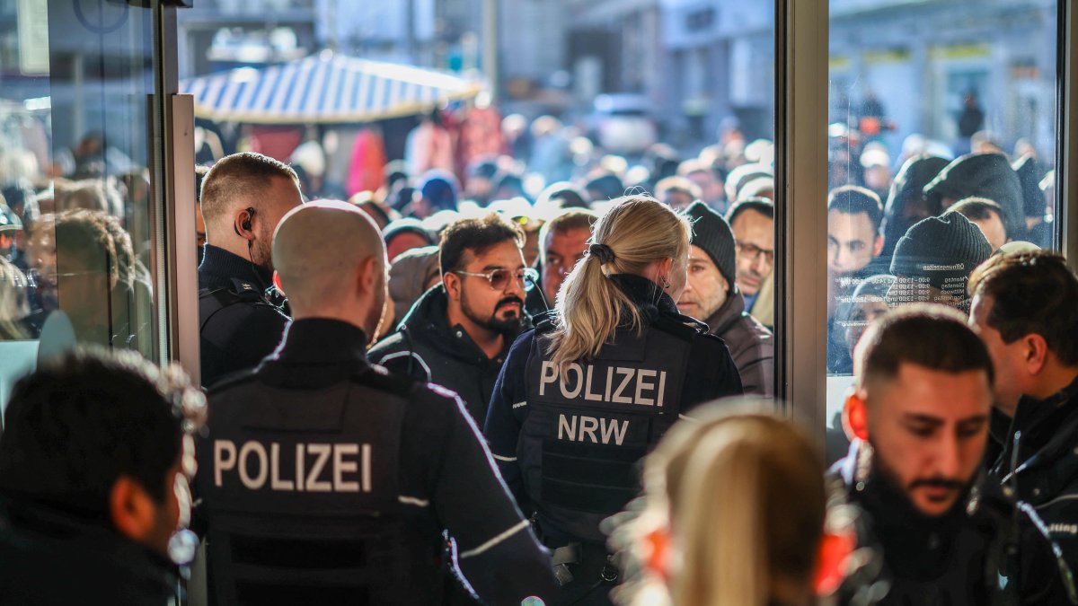 Policemen and concerned bank customers stand in front of a branch of the Sparkasse bank in Gelsenkirchen, western Germany, Dec. 30, 2025. (AFP Photo)