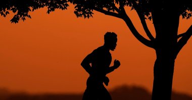 A man is silhouetted against the sky at sunset as he jogs in a park at the close of a hot summer day, Kansas City, Mo., U.S., Aug. 1, 2022. (AP Photo)