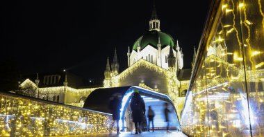 People walk on a bridge near the Academy of Fine Arts, decorated with lights for upcoming holidays, Sarajevo, Bosnia-Herzegovina, Dec. 21, 2025. (Reuters Photo)