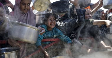 Internally displaced Palestinians, including children, hold pots as they gather to receive food from a charity kitchen, in Gaza City, Gaza Strip, Aug. 4, 2025. (EPA File Photo)