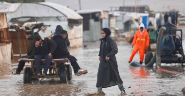 A displaced Palestinian woman walks along a street in floodwaters as the region experiences cold winter conditions in Al-Mawasi refugee camp in the southern Gaza Strip, Dec. 29, 2025. (AFP Photo)