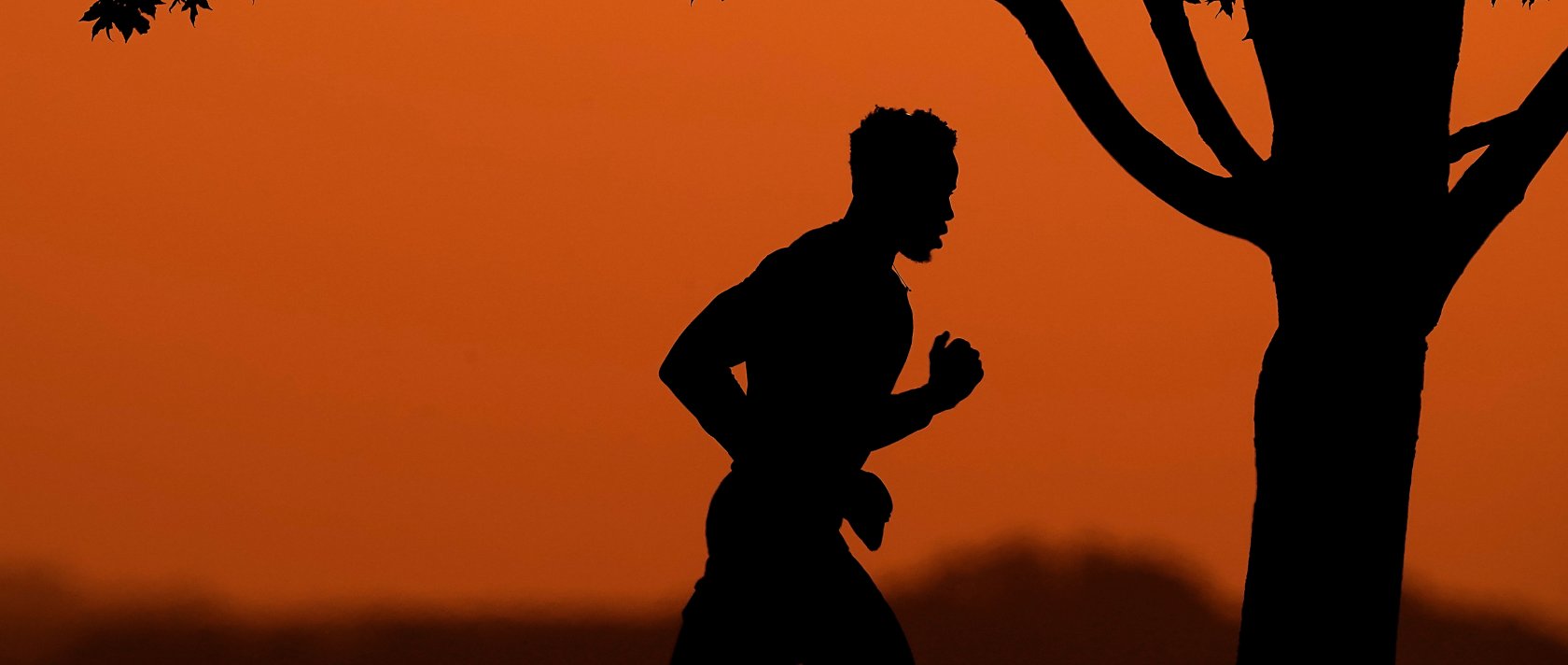A man is silhouetted against the sky at sunset as he jogs in a park at the close of a hot summer day, Kansas City, Mo., U.S., Aug. 1, 2022. (AP Photo)