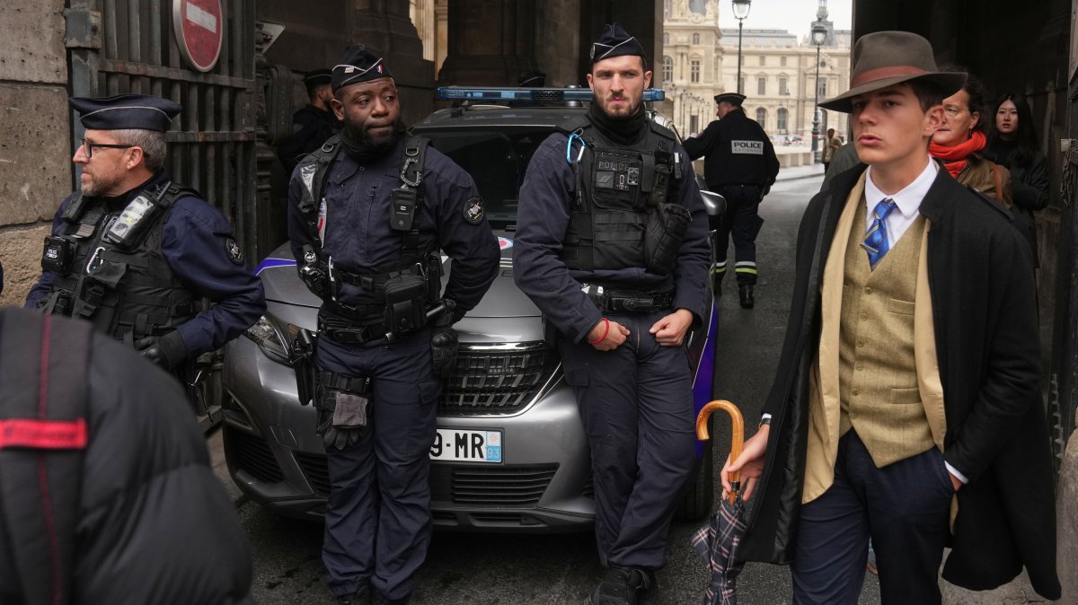 Pedro Elias Garzon Delvaux (R) walks past as police officers block an entrance to the Louvre after thieves carried out a daylight raid on French crown jewels, Paris, France, Oct. 19, 2025. (AP Photo)