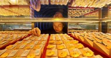 A salesperson adjusts gold jewellery for sale at a shop in Lianyungang, China, Dec. 24, 2025. (AFP Photo)