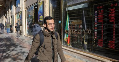 People walk past a sign at a currency exchange as the value of the Iranian Rial drops, in Tehran, Iran, Dec. 30, 2025. (Reuters Photo)