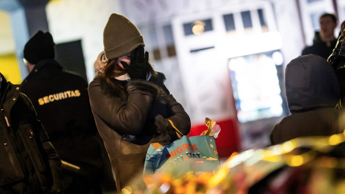 A mourner gestures in front of flowers and candles laid near the site where a fire ripped through a crowded bar during New Year's Eve celebrations in the Alpine ski resort town of Crans-Montana, Switzerland, Jan. 1, 2026. (AFP Photo)
