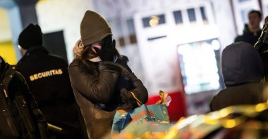 A mourner gestures in front of flowers and candles laid near the site where a fire ripped through a crowded bar during New Year's Eve celebrations in the Alpine ski resort town of Crans-Montana, Switzerland, Jan. 1, 2026. (AFP Photo)