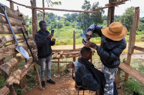 Barber and content creator Safari Martins uses a clothing iron as he shaves Ian Njenga in Kiambu, Kenya, Nov. 26, 2025. (AP Photo)