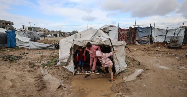Young displaced Palestinians exit a tent erected on waterlogged ground in the Bureij refugee camp as the region experiences cold winter conditions, Gaza Strip, Palestine, Dec. 29, 2025. (AFP Photo)