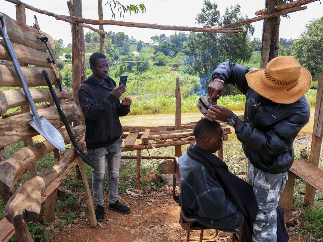 Barber and content creator Safari Martins uses a clothing iron as he shaves Ian Njenga in Kiambu, Kenya, Nov. 26, 2025. (AP Photo)