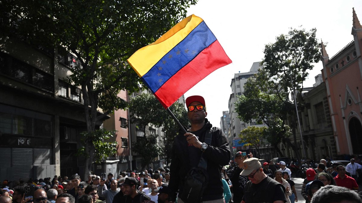 A supporter of President Nicolas Maduro holds a Venezuelan flag after U.S. forces captured Maduro after launching a "large scale strike", during a gathering near the Palacio de Miraflores in Caracas, Venezuela, Jan. 3, 2026. (AFP Photo)