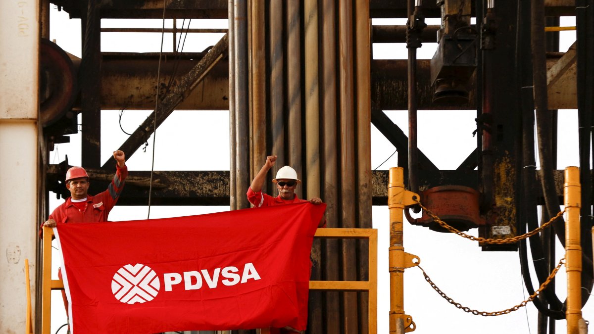 Oilfield workers hold a flag with the corporate logo of Venezuela's state oil company PDVSA, in a drilling rig at an oil well operated by them, in the oil rich Orinoco belt, near Cabrutica at the state of Anzoategui, Venezuela, April 16, 2015. (Reuters Photo)