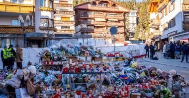 A mourner lays a flower bouquet at a makeshift memorial near the Constellation bar in honor of the victims of the fire that ripped through the venue in the luxury Alpine ski resort on New Year's Eve, in Crans-Montana, Switzerland, Jan. 4, 2026. (AFP Photo)