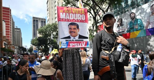 An armed supporter of ousted Venezuela's President Nicolas Maduro stands next to another one holding a poster of him during a demonstration a day after he was captured in a U.S. strike, in Caracas, Venezuela, Jan. 4, 2026. (AFP Photo)