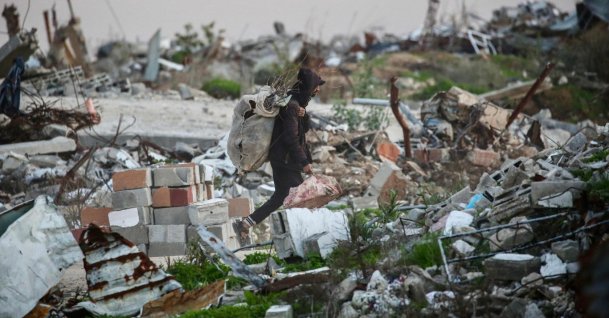 A Palestinian man carries firewood amid the ruins of destroyed buildings in the Nuseirat refugee camp in the central Gaza Strip, Palesitne, Dec. 31, 2025. (AFP Photo)