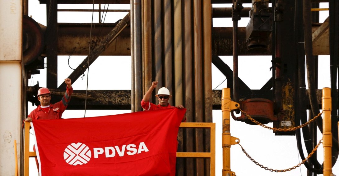 Oilfield workers hold a flag with the corporate logo of Venezuela's state oil company PDVSA, in a drilling rig at an oil well operated by them, in the oil rich Orinoco belt, near Cabrutica at the state of Anzoategui, Venezuela, April 16, 2015. (Reuters Photo)