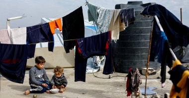 Palestinian children sit among hanging clothes, on New Year's Eve, Jabalia, northern Gaza Strip, Palestine, Dec. 31, 2025. (Reuters Photo)
