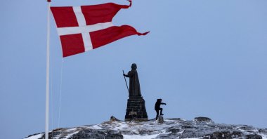 A man walks as Danish flag flutters next to Hans Egede Statue ahead of a March 11 general election in Nuuk, Greenland, March 9, 2025. (Reuters Photo)