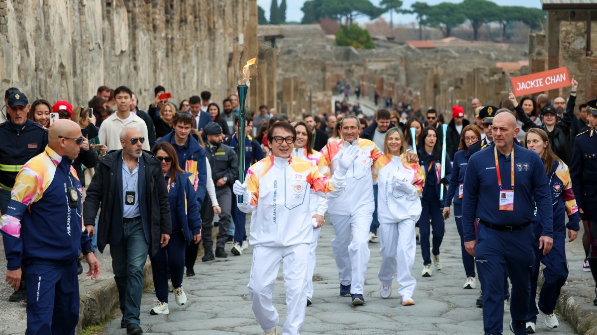 Actor Jackie Chan holds the Olympic torch as it passes through the Archaeological Park, Pompeii, Italy, Dec. 22, 2025. (AP Photo)