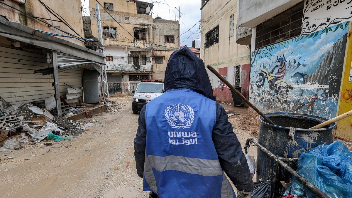 A man collects trash while wearing a jacket bearing the logo of the United Nations Relief and Works Agency for Palestine Refugees in the Near East (UNRWA), along a street in the city of Jenin in the occupied West Bank, Jan. 30, 2024. (AFP Photo)