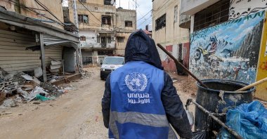 A man collects trash while wearing a jacket bearing the logo of the United Nations Relief and Works Agency for Palestine Refugees in the Near East (UNRWA), along a street in the city of Jenin in the occupied West Bank, Jan. 30, 2024. (AFP Photo)