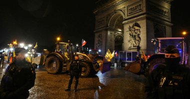 French police officers stand next to parked tractors with the Arc de Triomphe in the background during a demonstration of farmers to push the French government to block the Mercosur trade deal, Paris, France, Jan. 8, 2026. (AFP Photo)