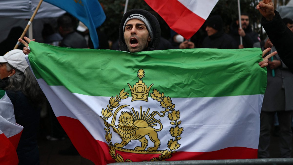An anti-Iranian government protester holds the Iranian flag before the 1979 revolution with the Lion and Sun emblems during a gathering outside the Iranian Embassy, central London, Britain, Jan. 9, 2026. (AFP Photo)