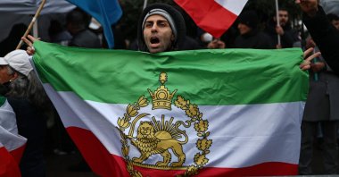 An anti-Iranian government protester holds the Iranian flag before the 1979 revolution with the Lion and Sun emblems during a gathering outside the Iranian Embassy, central London, Britain, Jan. 9, 2026. (AFP Photo)