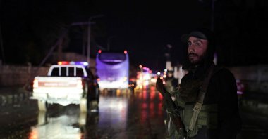 A Syrian security force officer stands guard as buses carrying YPG members leave a neighborhood, Aleppo, Syria, Jan. 11, 2026. (AFP Photo)
