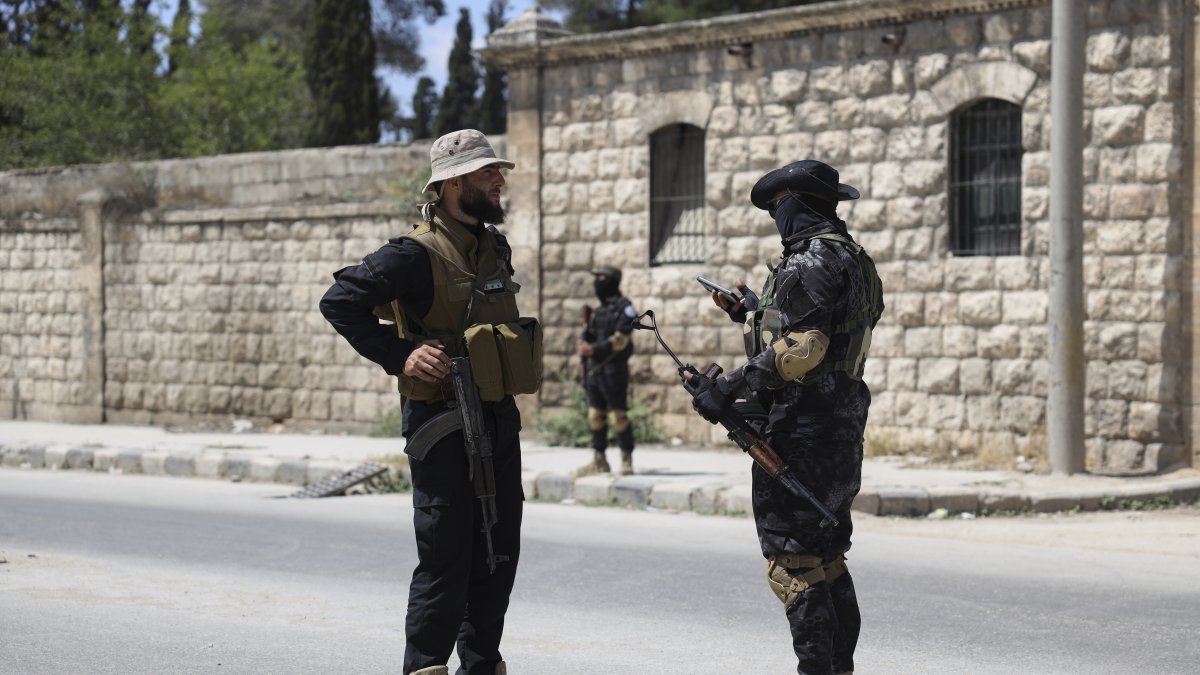 A member of the government security forces (L) speaks with a YPG member during a prisoner exchange, Sheikh Maqsoud neighborhood, Aleppo, Syria, June 2, 2025. (AP Photo)